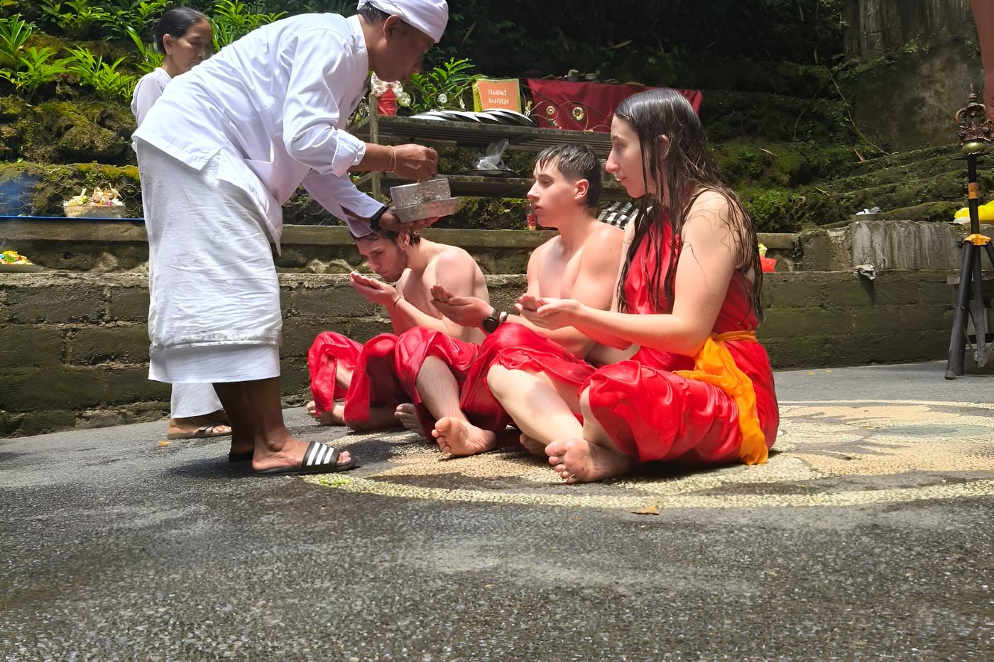Balinese priest leading a melukat water blessing for a family