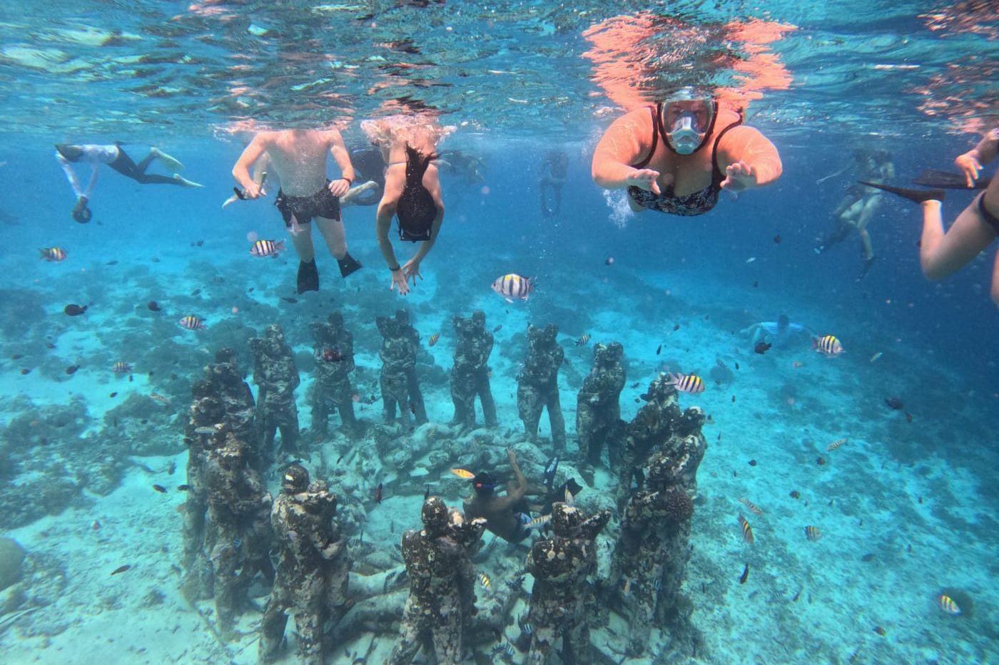 Group snorkelling over the circle of statues at Gili Meno